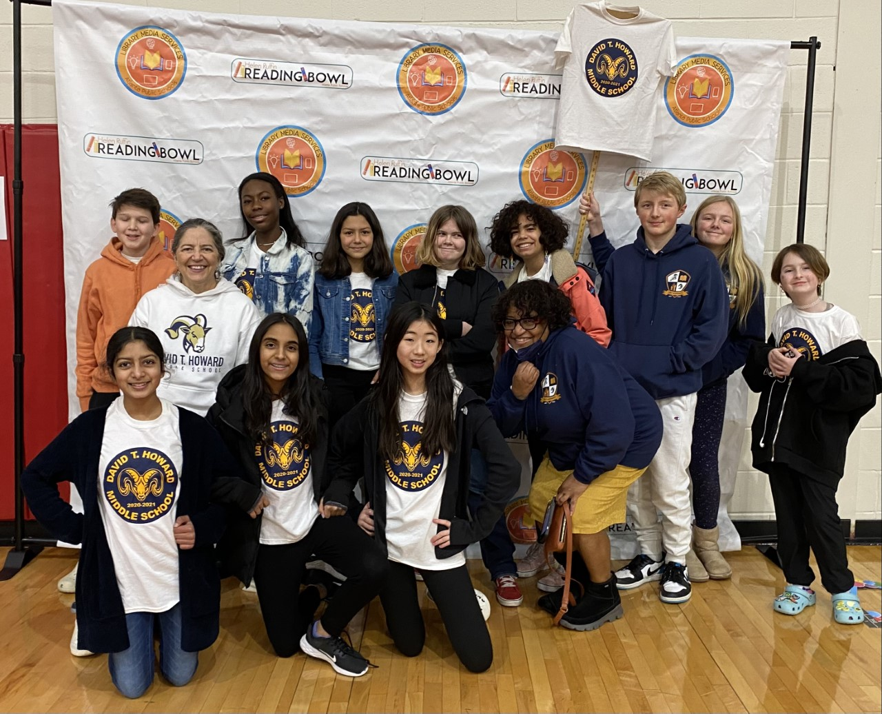 A photo of a group of students and teachers in front of a Reading Bowl banner